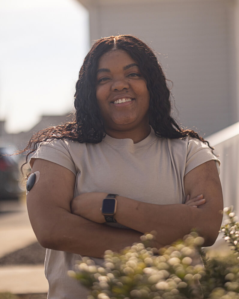An Eversense user standing outdoors with her smart CGM transmitter on her arm